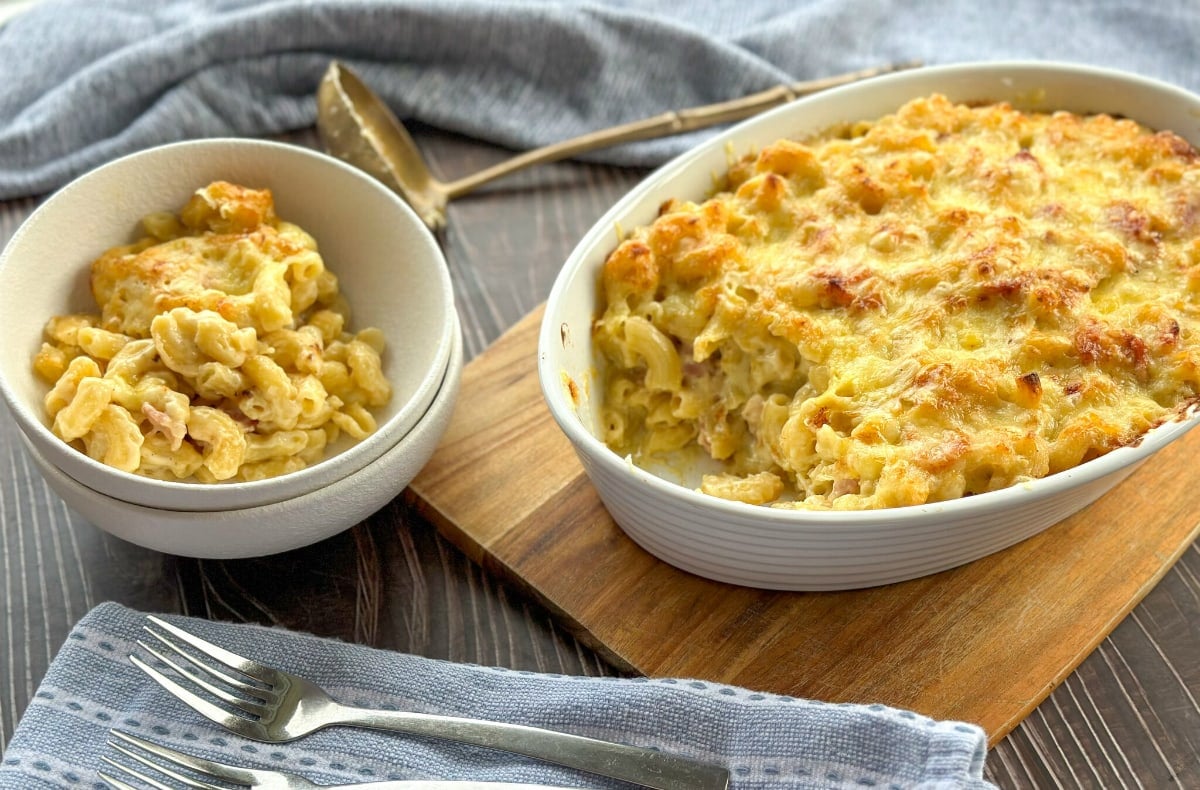 White Bowl of Macaroni Cheese next to Serving dish of Macaroni Cheese