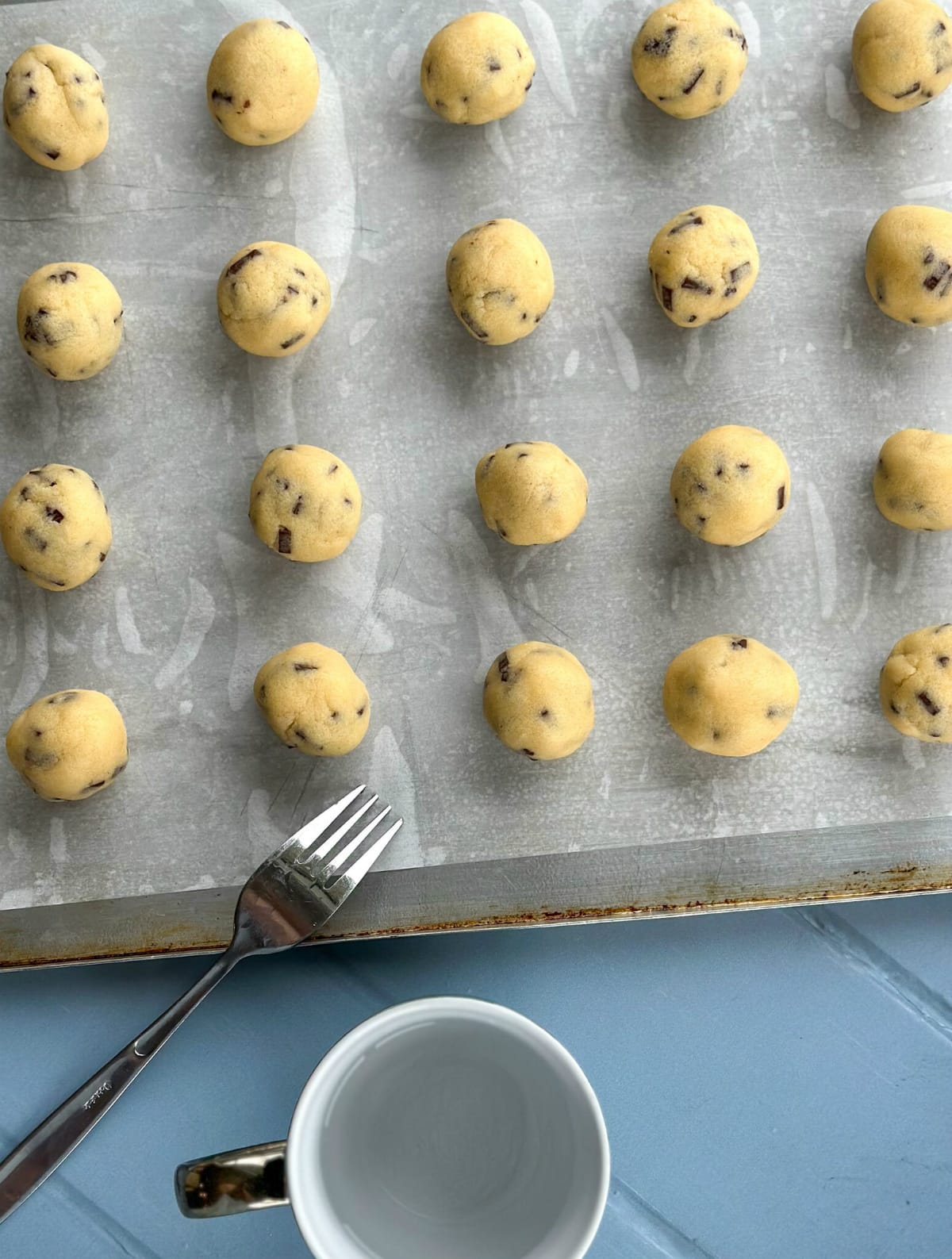 Balls of cookie dough, a fork and a glass of water ready to press down the cookies 