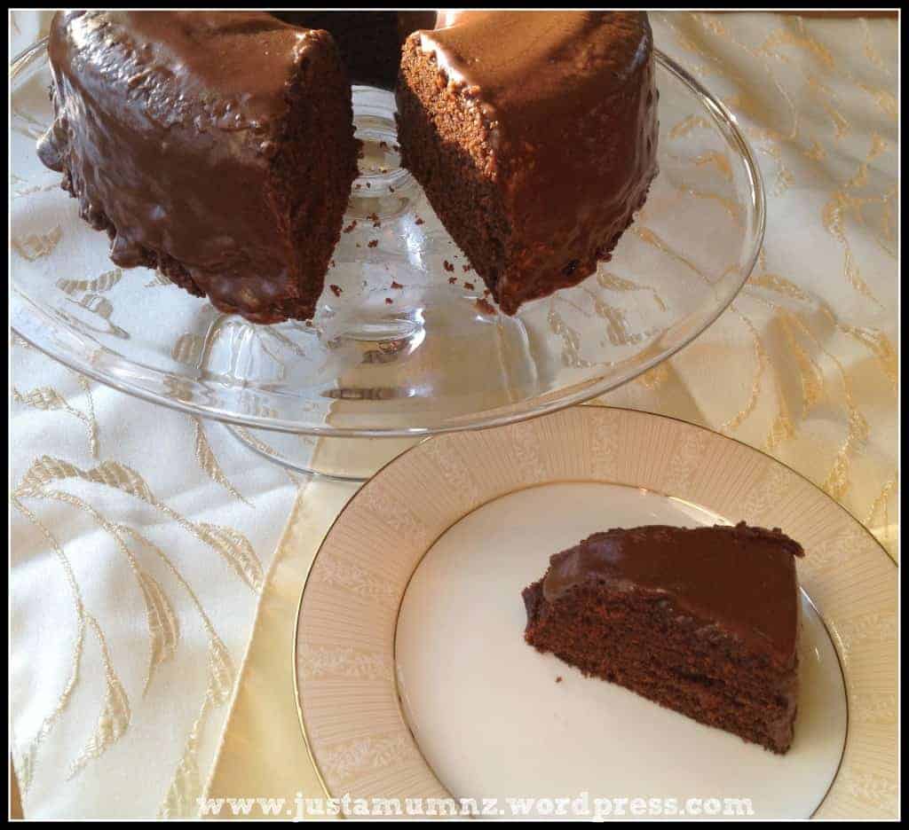 A piece of chocolate cake and a full chocolate cake with a piece cut out. 
