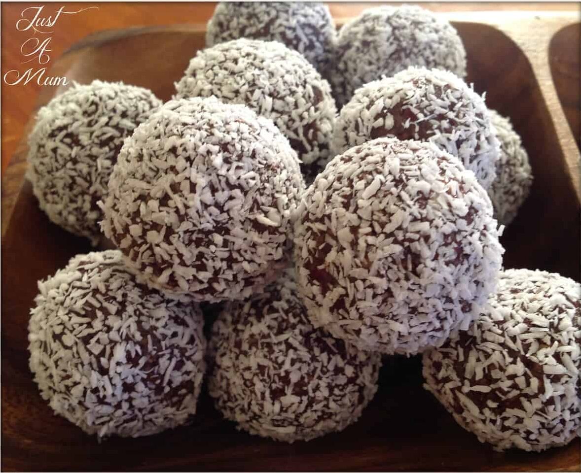 Cranberry Date Cashew Bliss Balls covered in coconut in a wooden bowl
