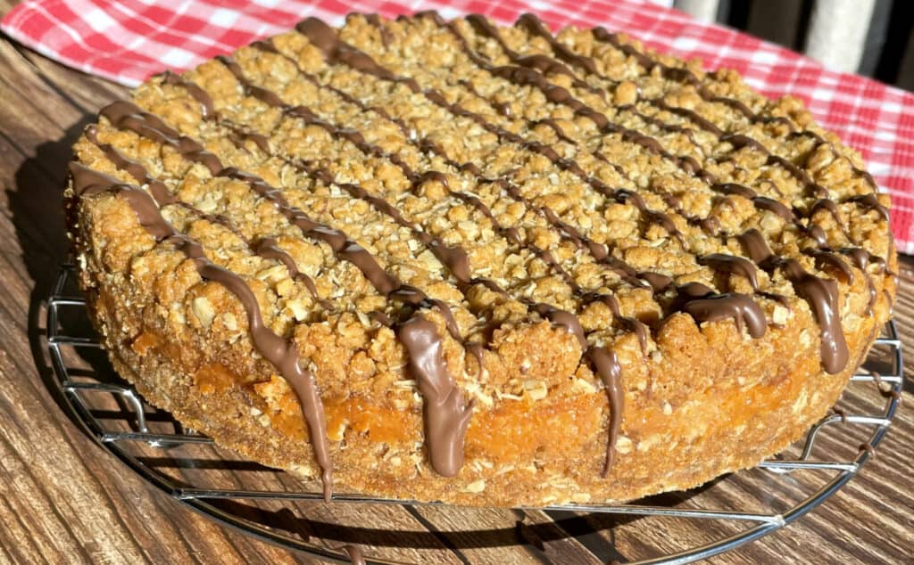 A close up of Anzac slice showing the chocolate topping and caramel centre.
