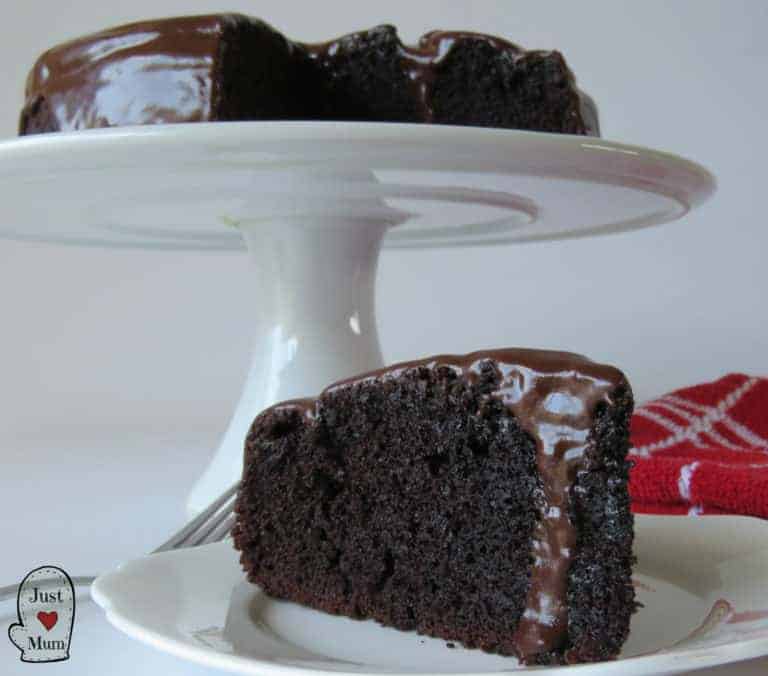 Slice of Chocolate Cake, With The rest of the cake behind it on a serving platter