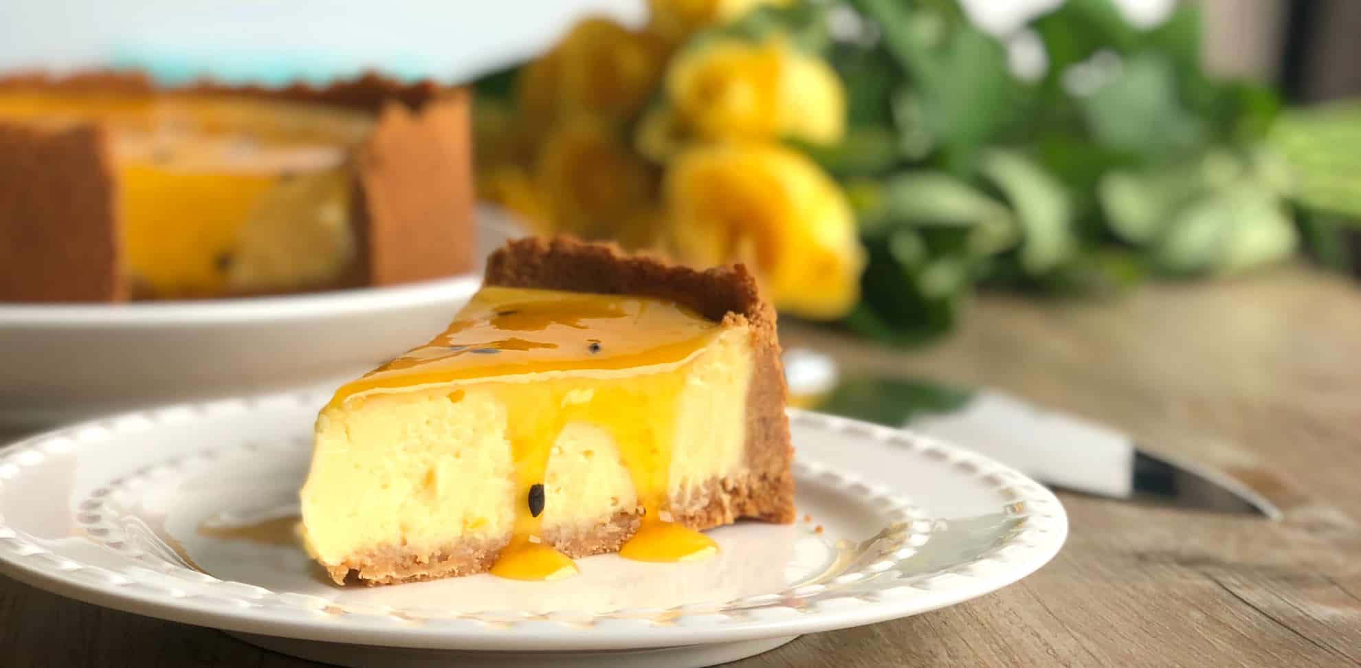 Slice of Just A Mums baked cheesecake with barkers passionfruit sauce