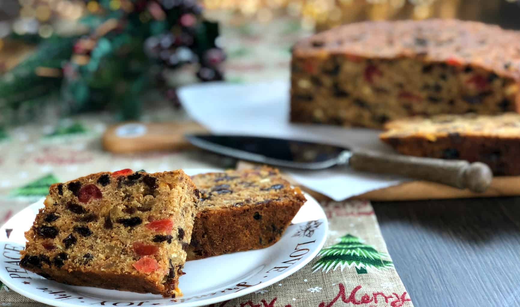 Two Slices of Christmas cake, with remainder of cake in the background