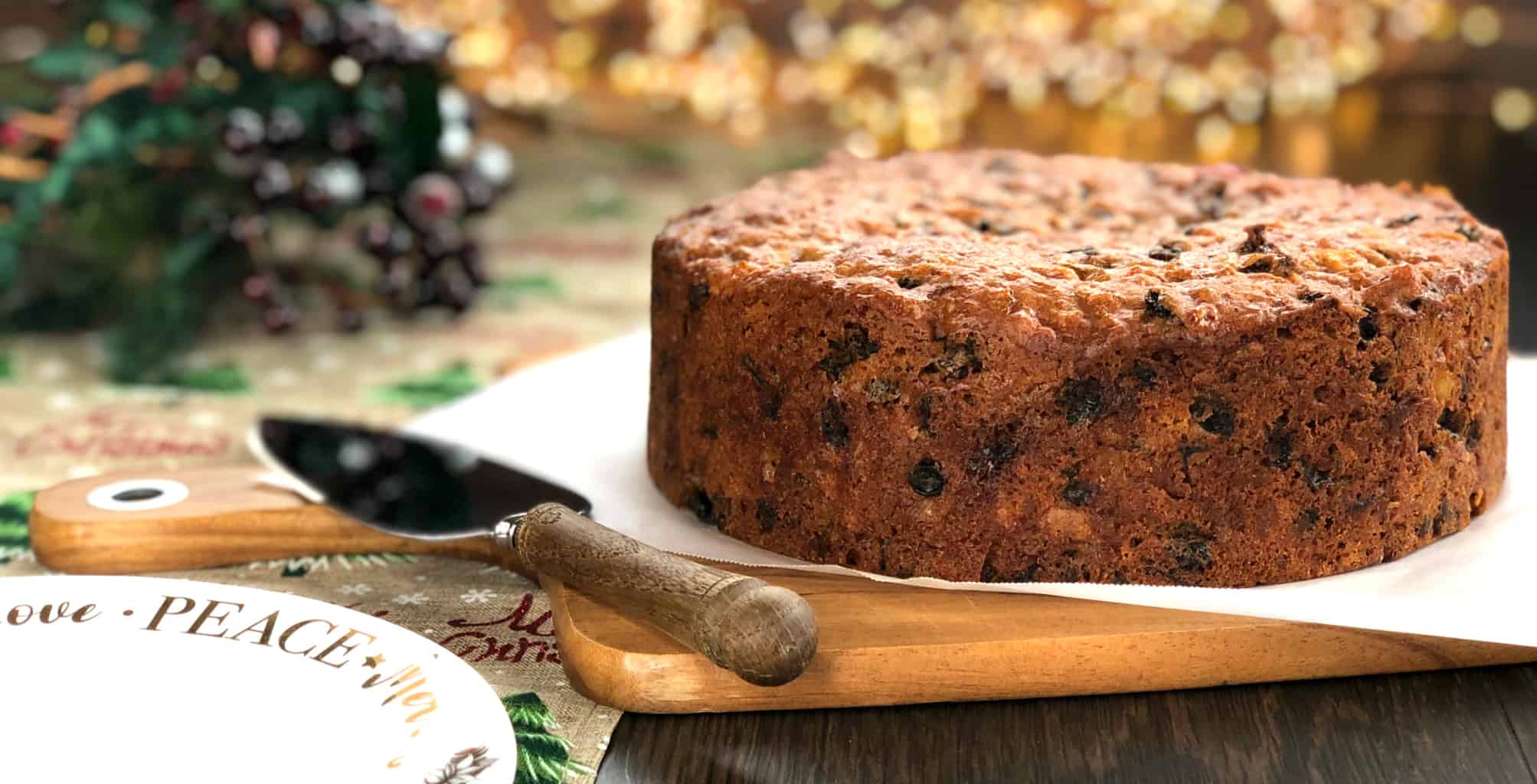 Delicious Christmas Cake on a chopping board with a serving slice next to it