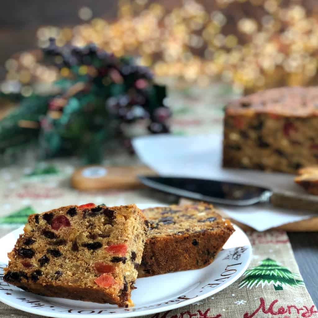 Two Slices of Delicious Christmas Cake with A Christmas Branch of berries in the background