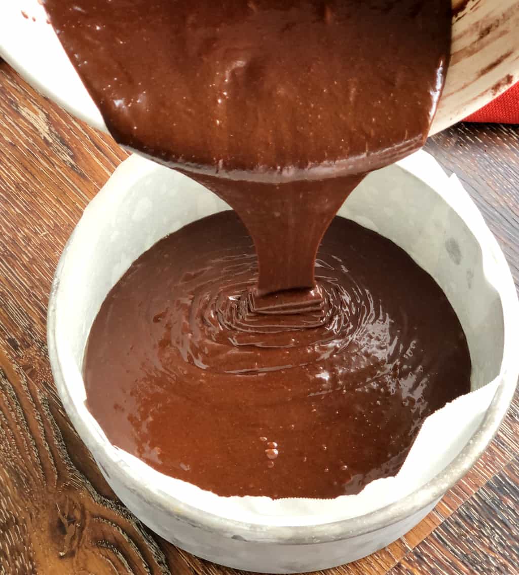 Pouring chocolate cake batter into the lined tin