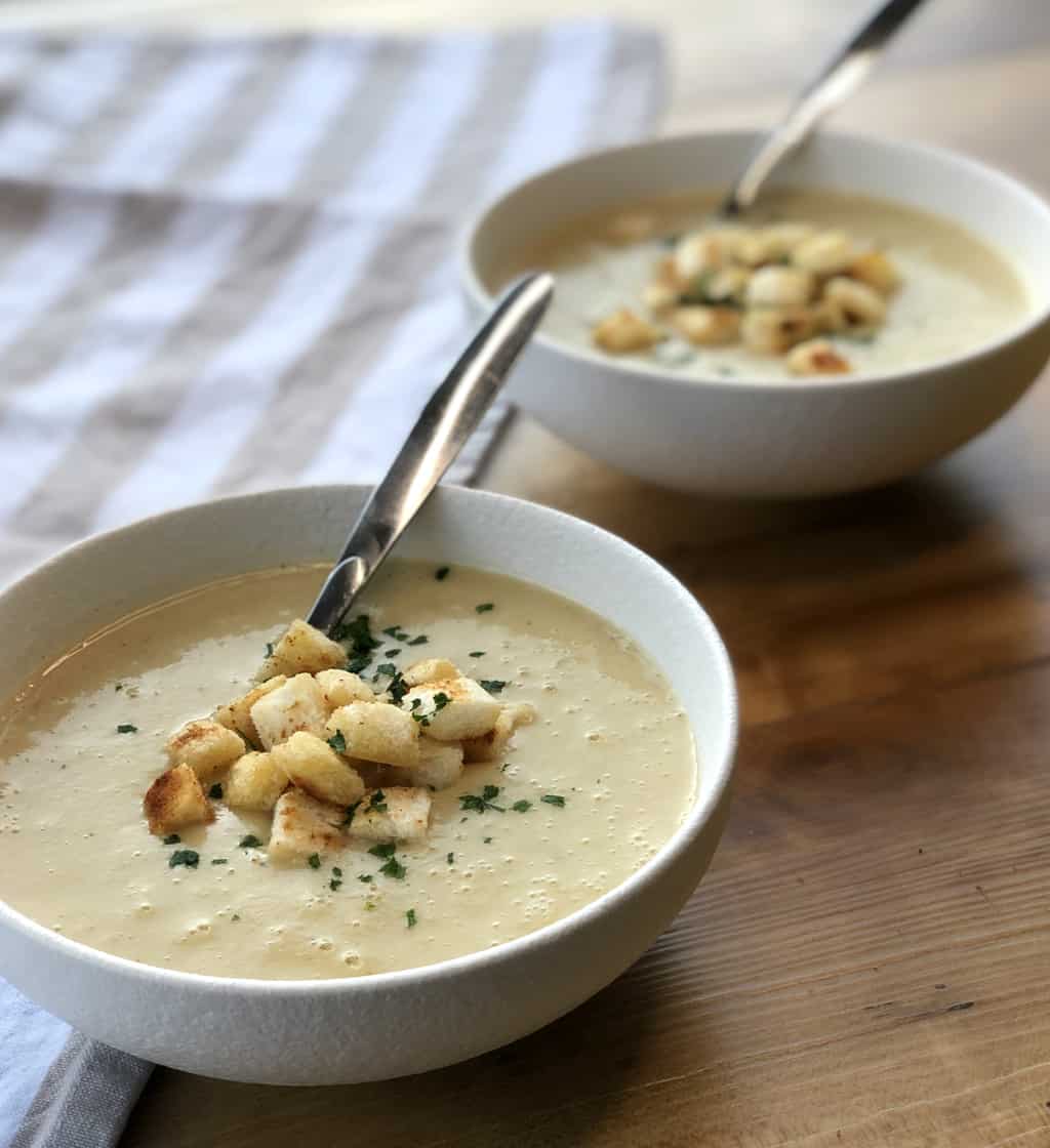 Two bowls of potato and leek soup with croutons