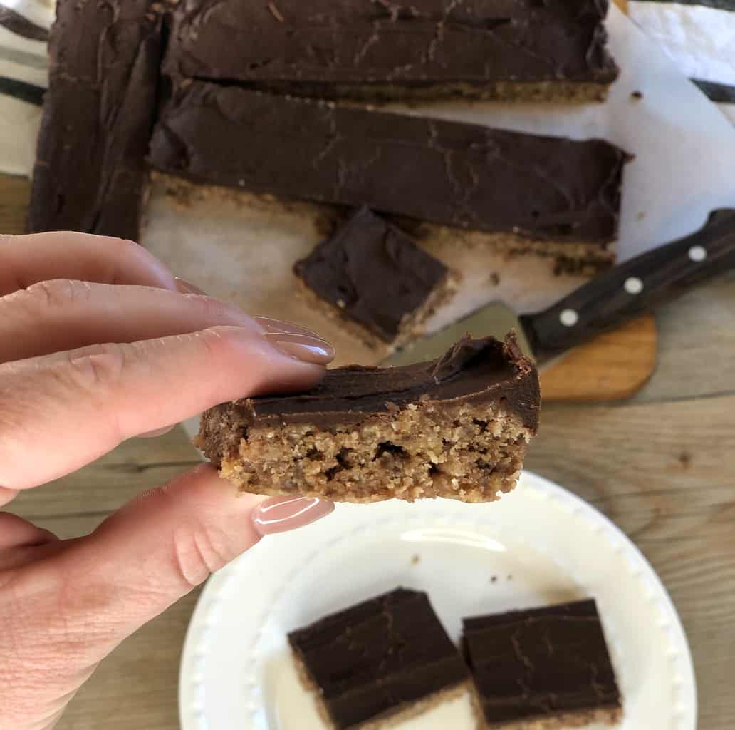 A hand holding a piece of baking close to the camera with the rest of the baking in the background