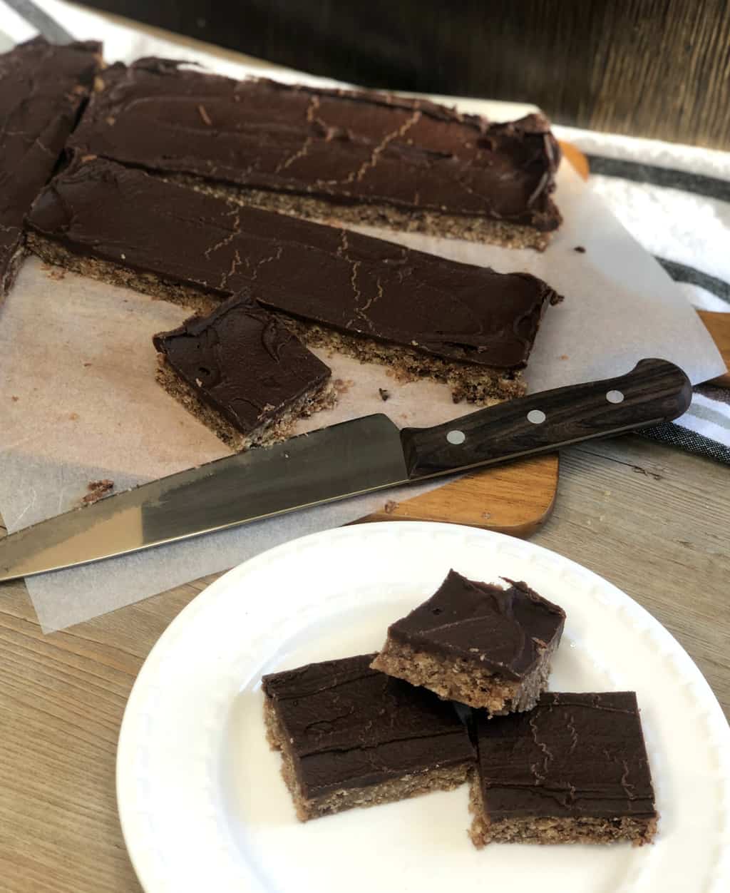 An overhead shot showing the sliced baked slice and three pieces on a white plate and a sharp knife