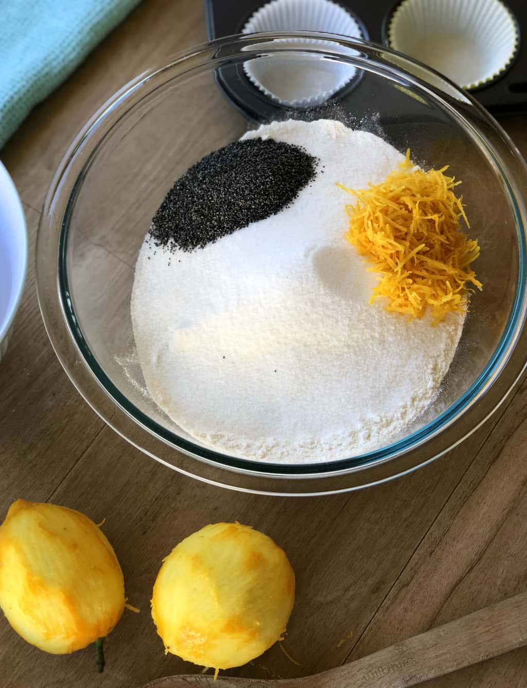 Dry ingredients in a bowl for the lemon and poppy seed muffins and two zested lemons