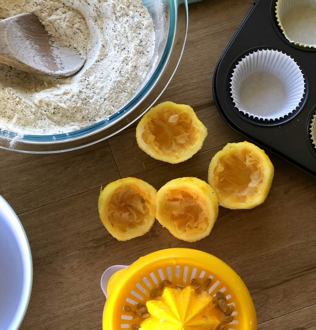 Prepared dry ingredients and 4 lemon halves that have been juiced in a lemon juicer