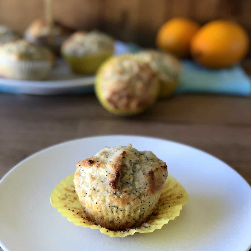 Lemon and Poppy Seed muffin in the foreground with the cupcake case peeled back. 