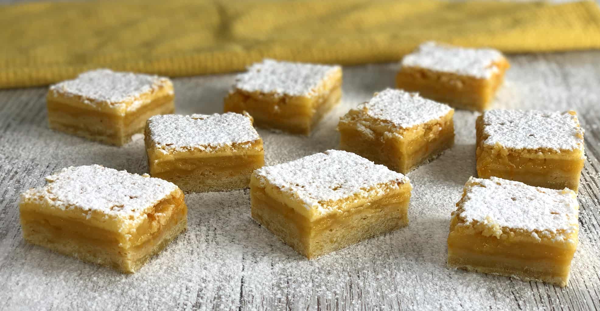 Close up photo of the lemon squares individually sliced and dusted in icing sugar on a white table 