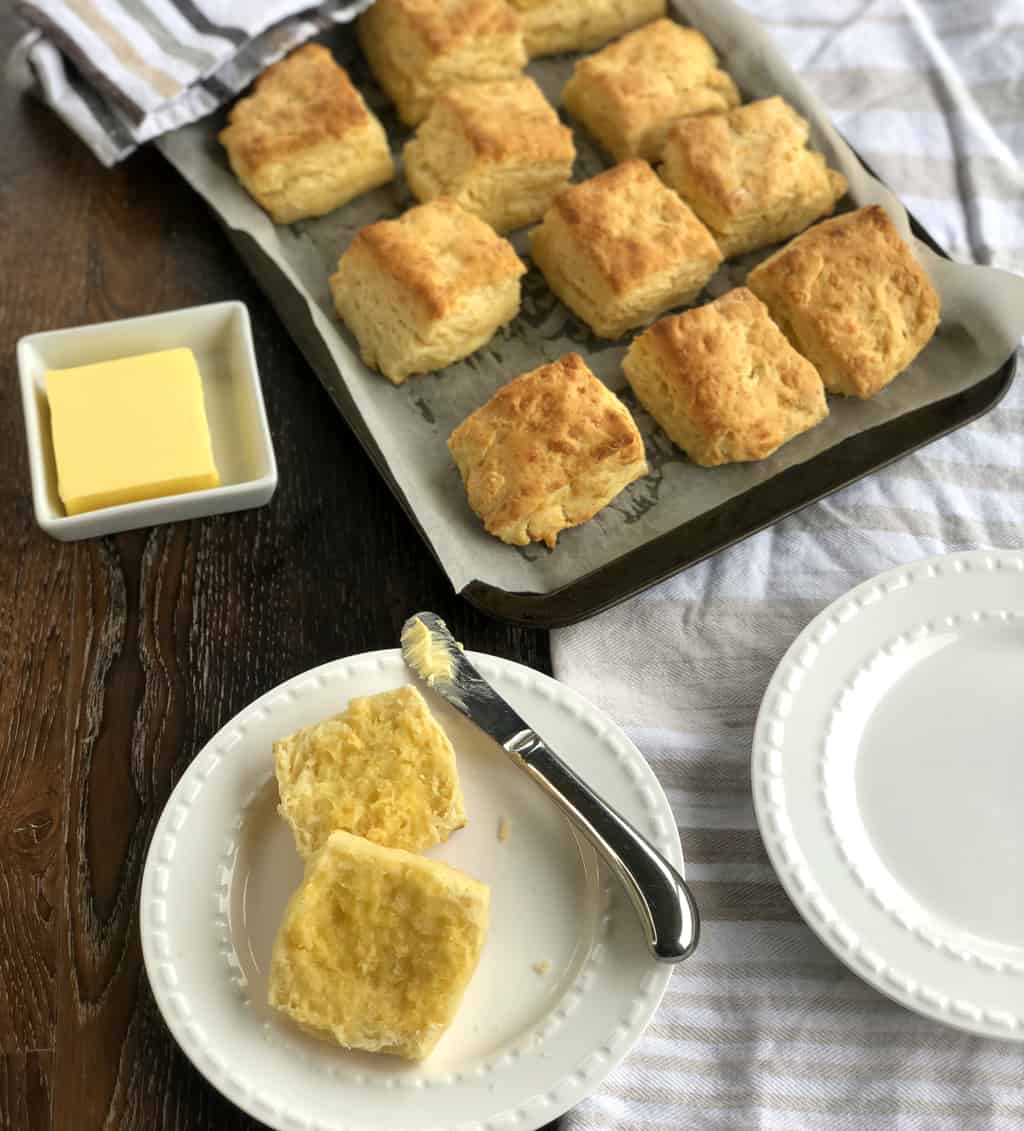 Overhead photograph of warm scones spread with melted butter and a tray of scones 