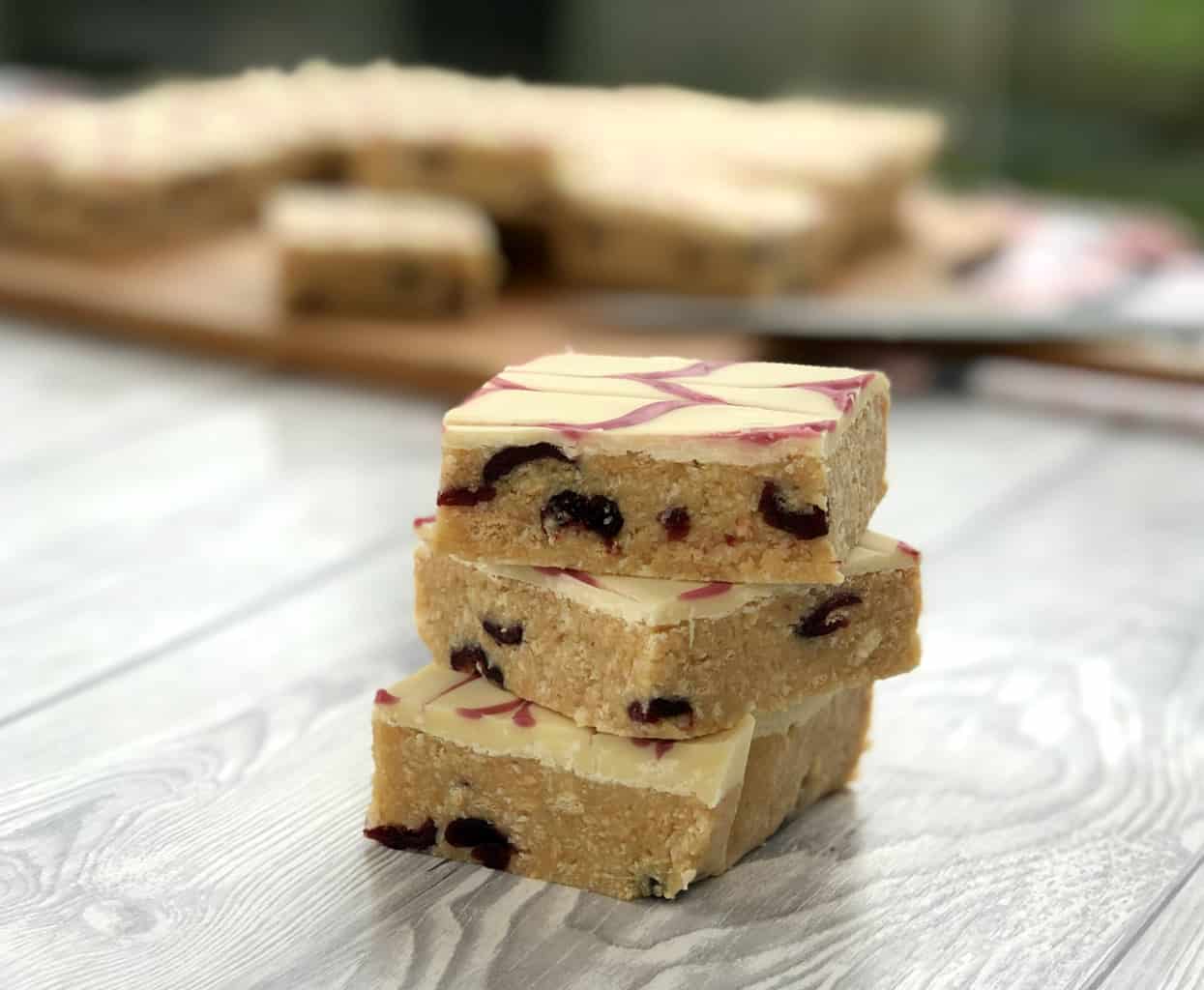 Close up photo of 3 pieces of no bake slice showing cranberries and coconut 