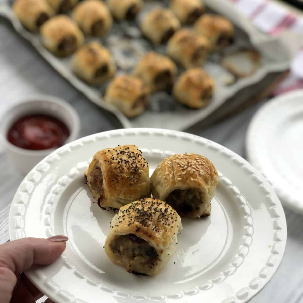 A white plate with three freshly baked sausage rolls 