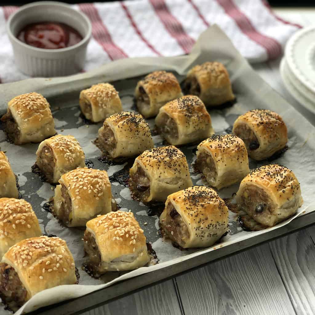 Warm Sausage Rolls on a baking tray with a ramekin of tomato sauce