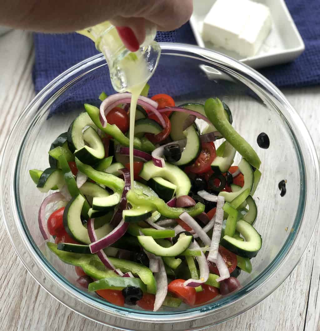 Pouring dressing over the greek salad 