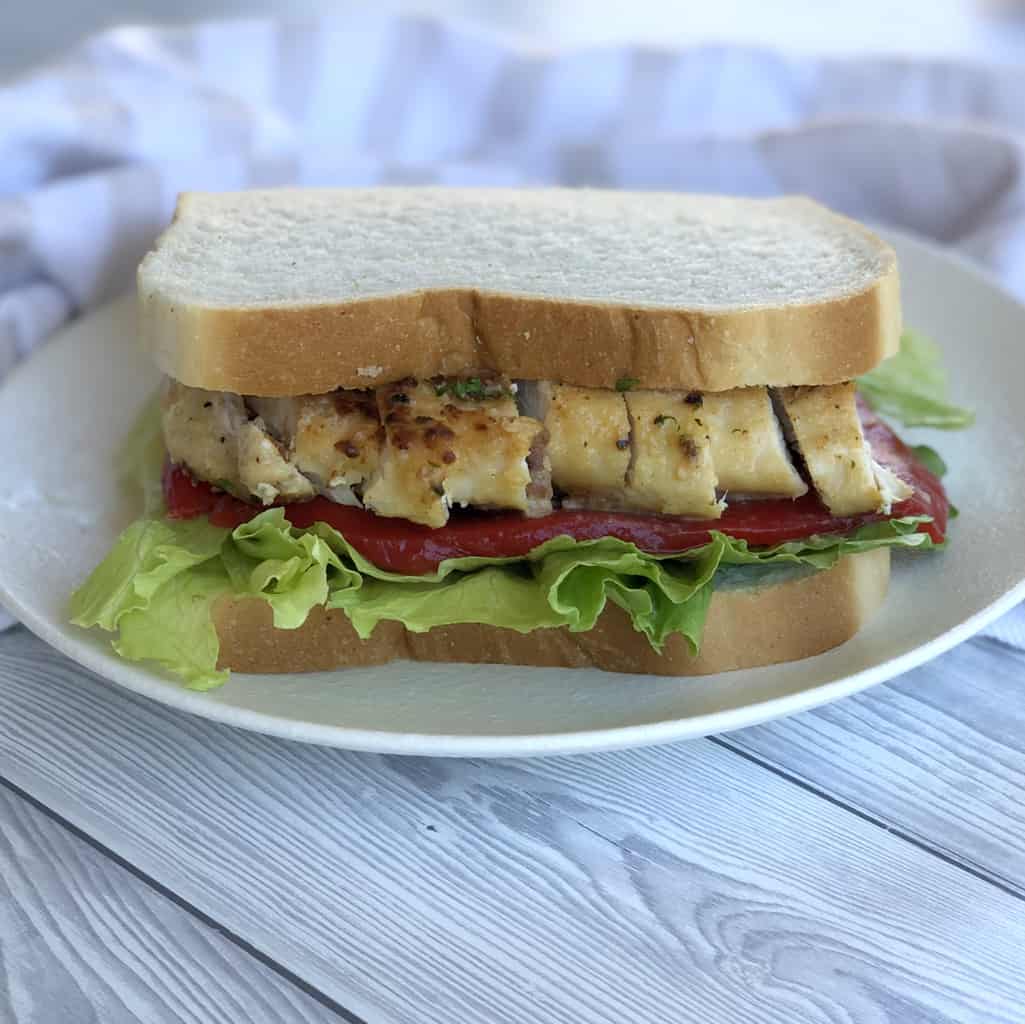 White bread sandwich with creamy chicken, lettuce and roasted red peppers. 