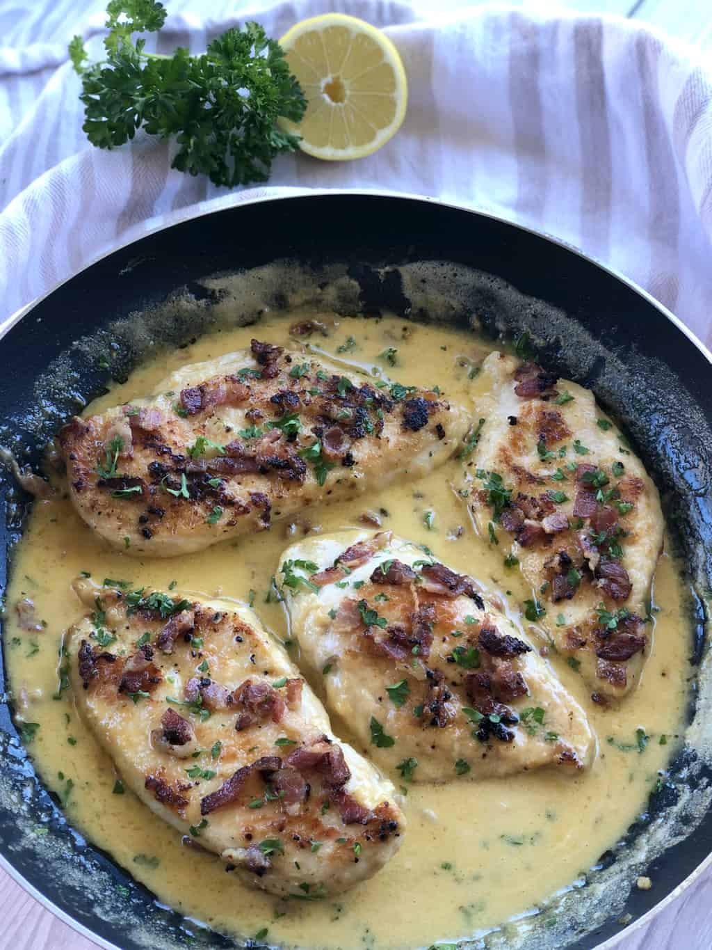 Creamy Chicken dish in a frying pan showing lemon and parsley as garnish