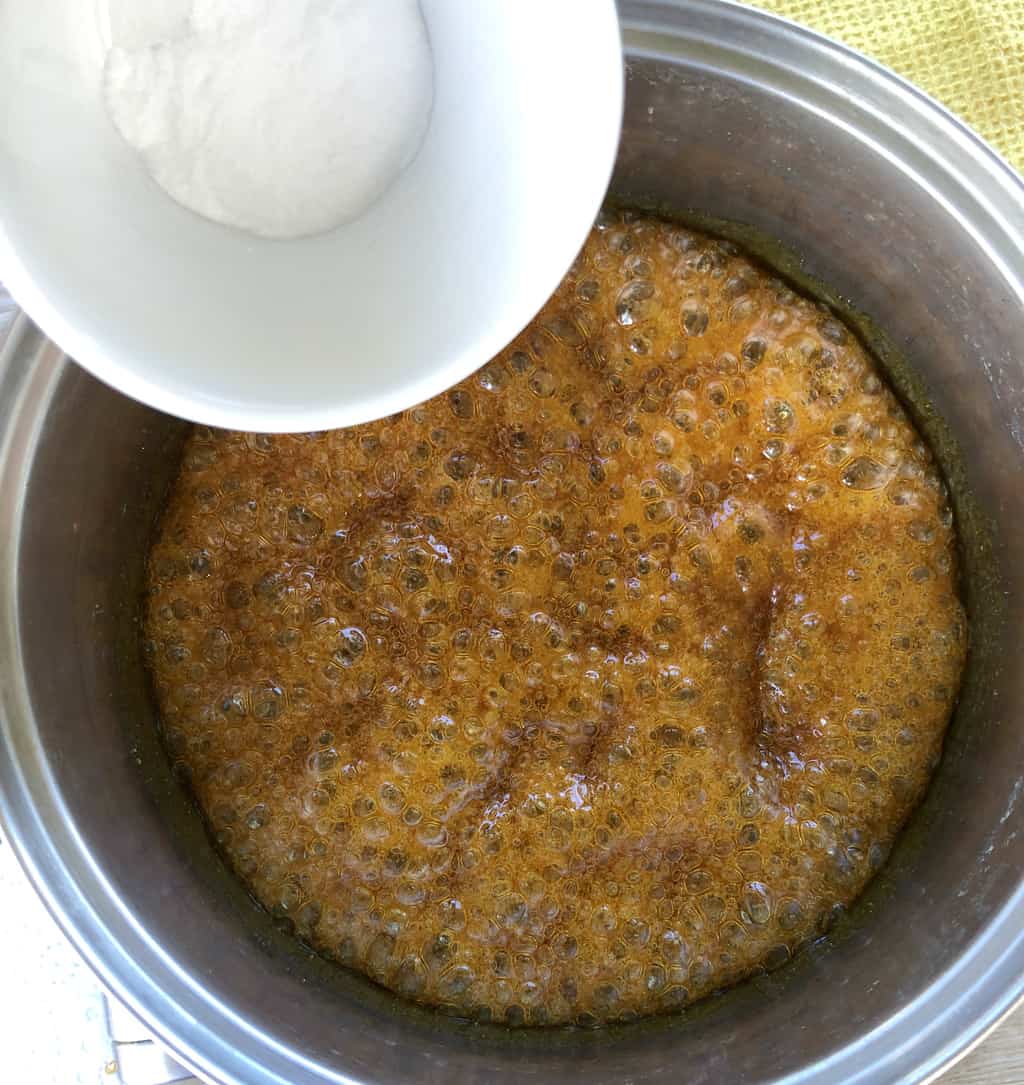 Pouring baking soda into the boiled hokey pokey mixture of golden syrup and sugar 