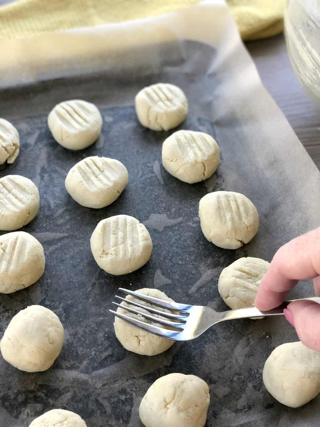 Pressing a fork into the top of the rounds of biscuit dough to make a pretty pattern