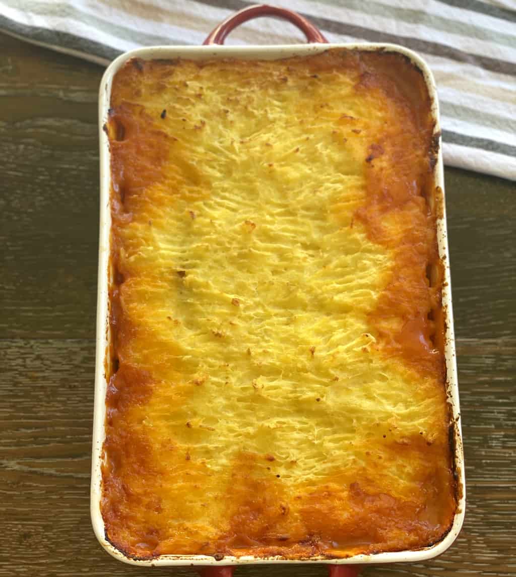 Comfort Food dish of golden brown shepherds pie with devilled sausages filling