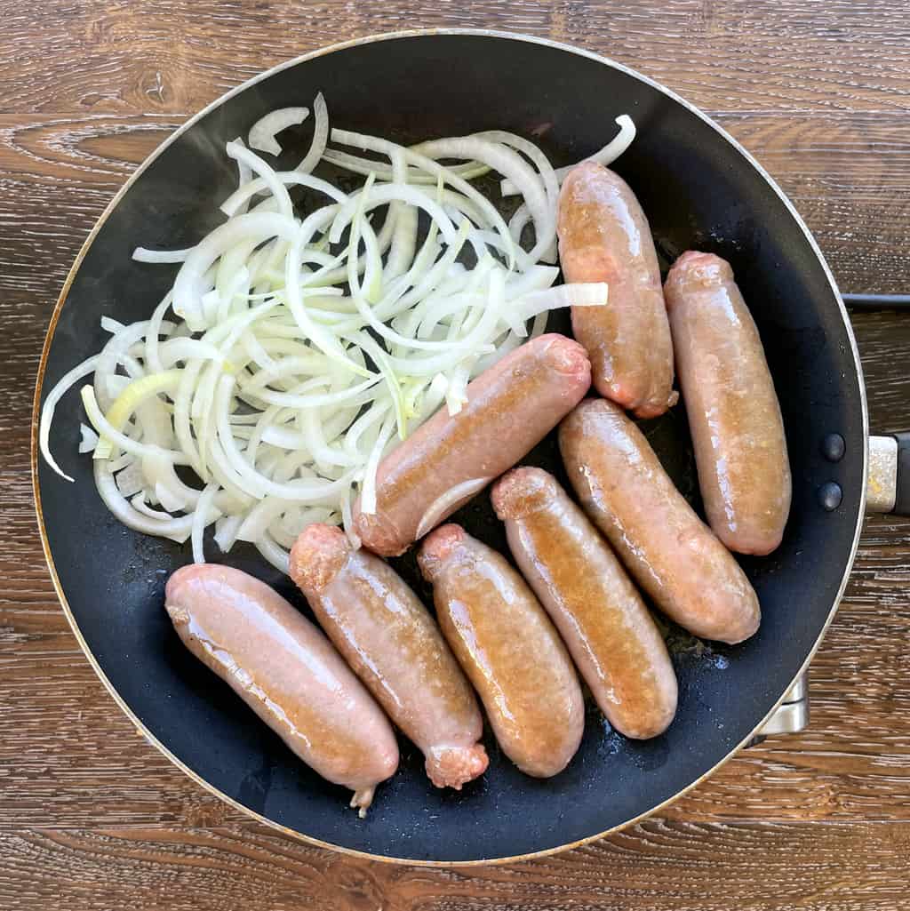 Onions and Sausages in a frying pan browning 