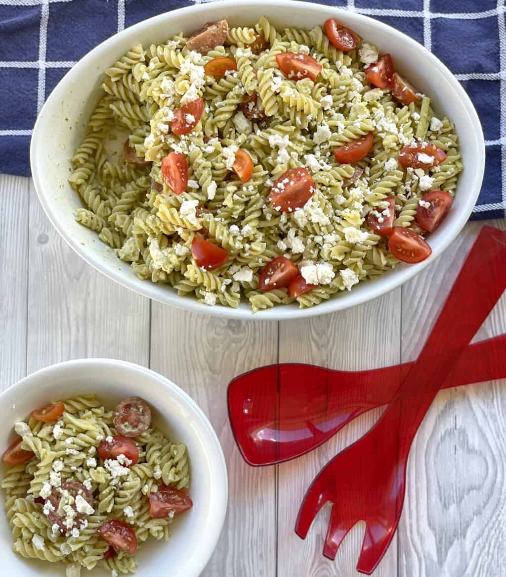 Pesto Pasta Salad in a large white bowl and a small serving in a smaller white bowl 