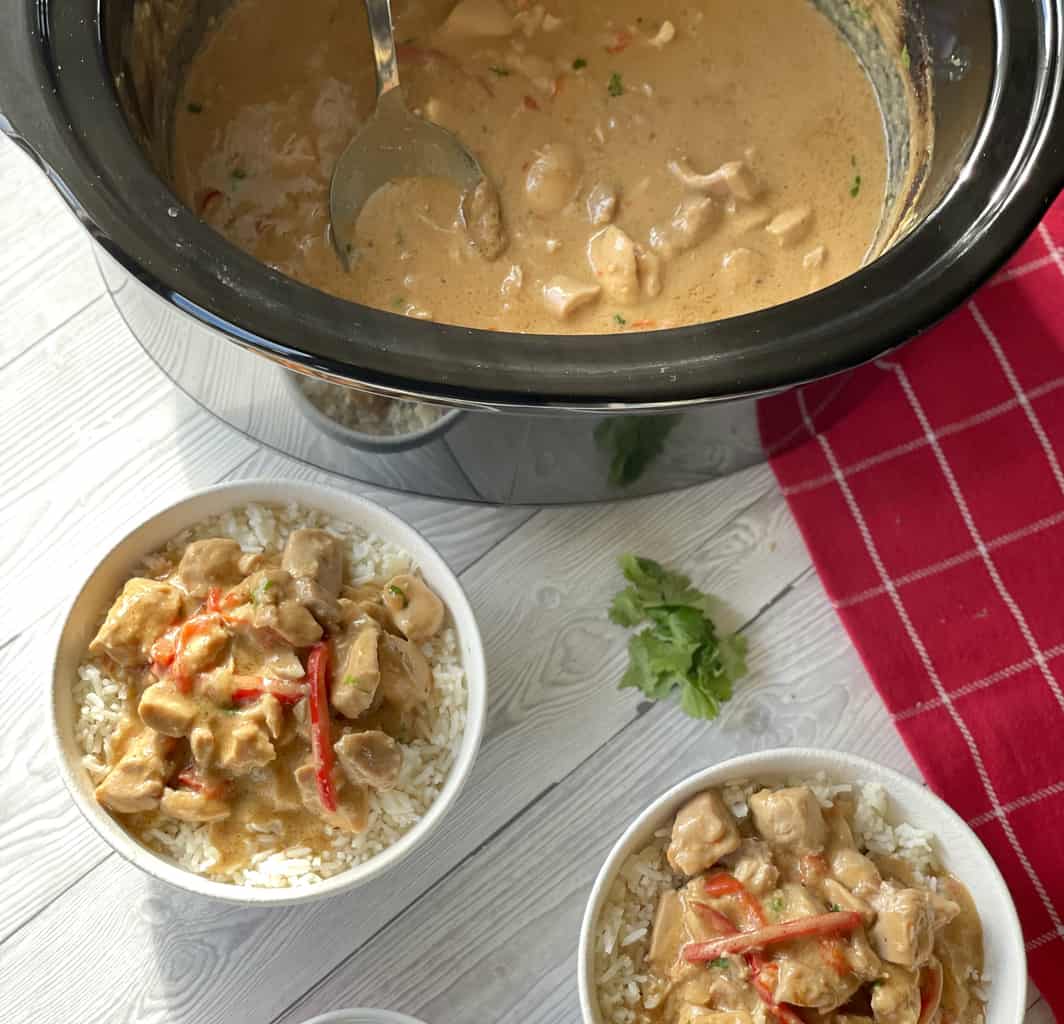 Slow Cooker with satay chicken, and two bowls of white rice with servings of the satay chicken