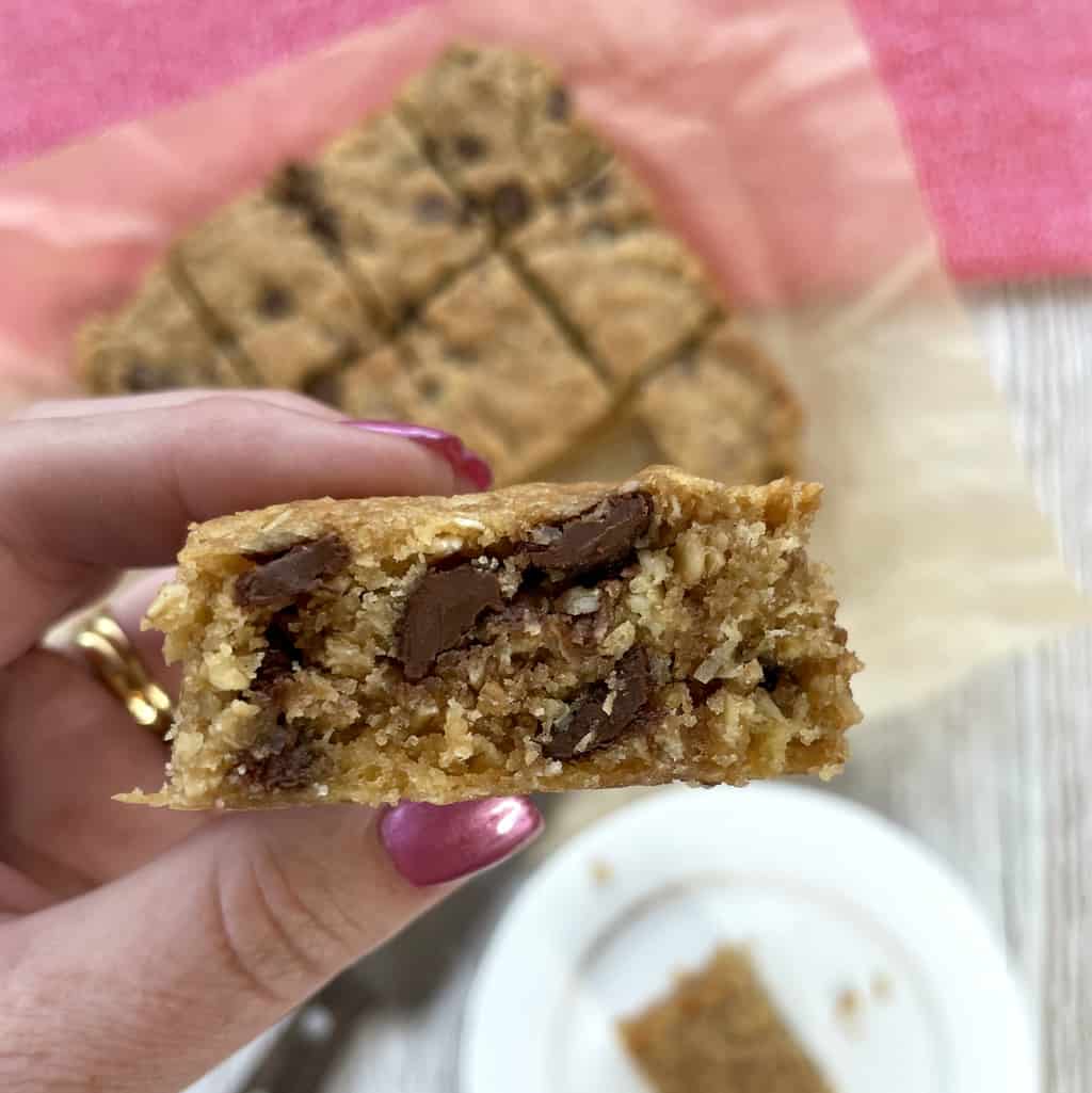 A hand holding a piece of oat slice with chocolate drops 