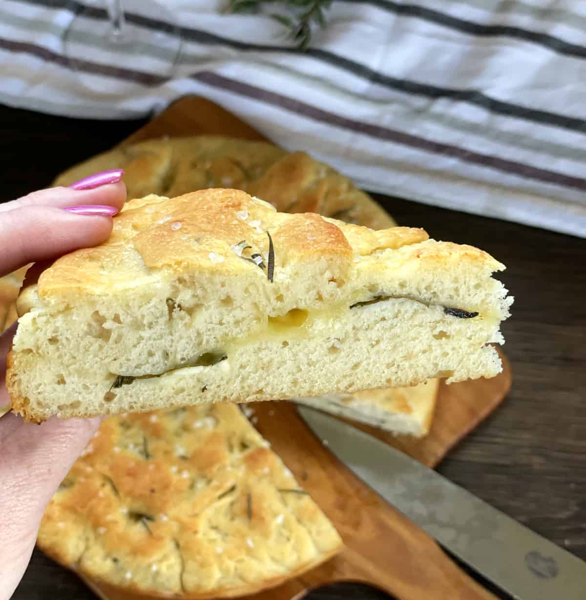 A hand holding a fresh slice of stuffed focaccia 