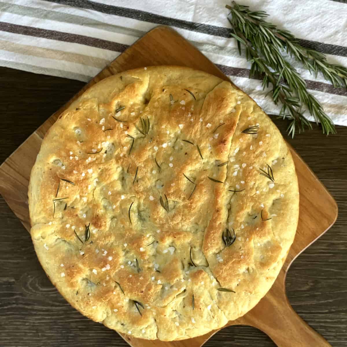 Overehead photograph of focaccia bread infused with a rosemary and garlic infused olive oil topped with sea salt and rosemary 