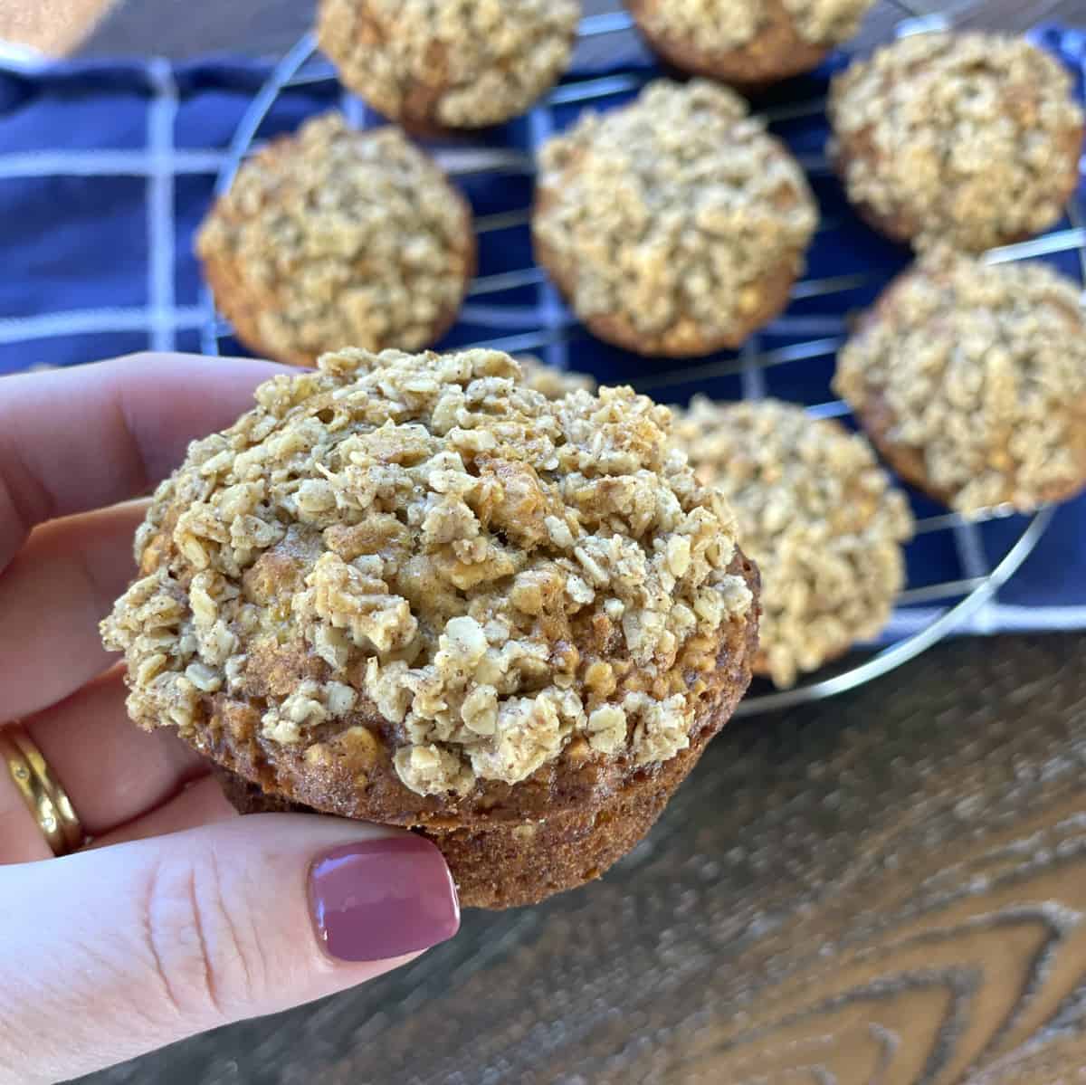 Holding a muffin in a hand showing the golden brown crunchy topping