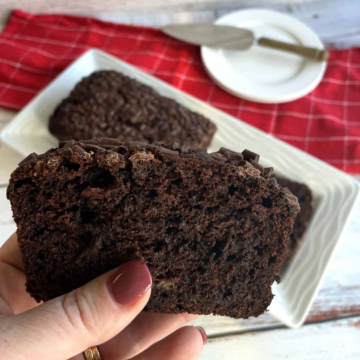 A hand holding a slice of double chocolate banana loaf 