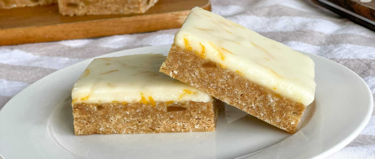Close up photo of two pieces of lemon and ginger no bake slice 