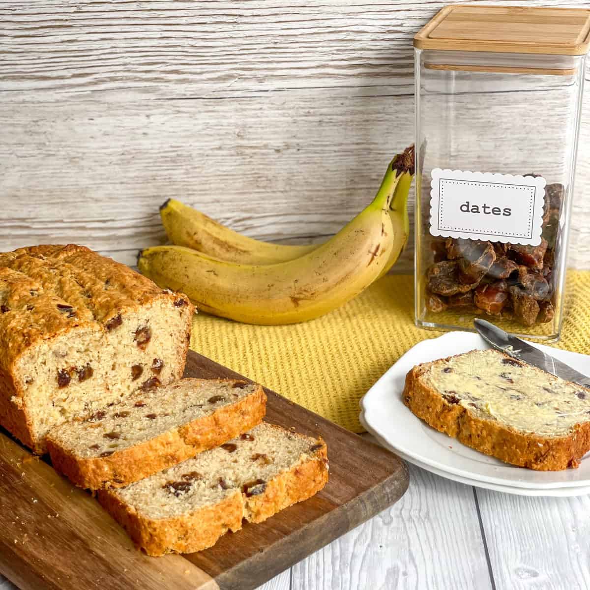 Container of Dates and fresh bananas next to a freshly baked loaf of banana and date loaf 