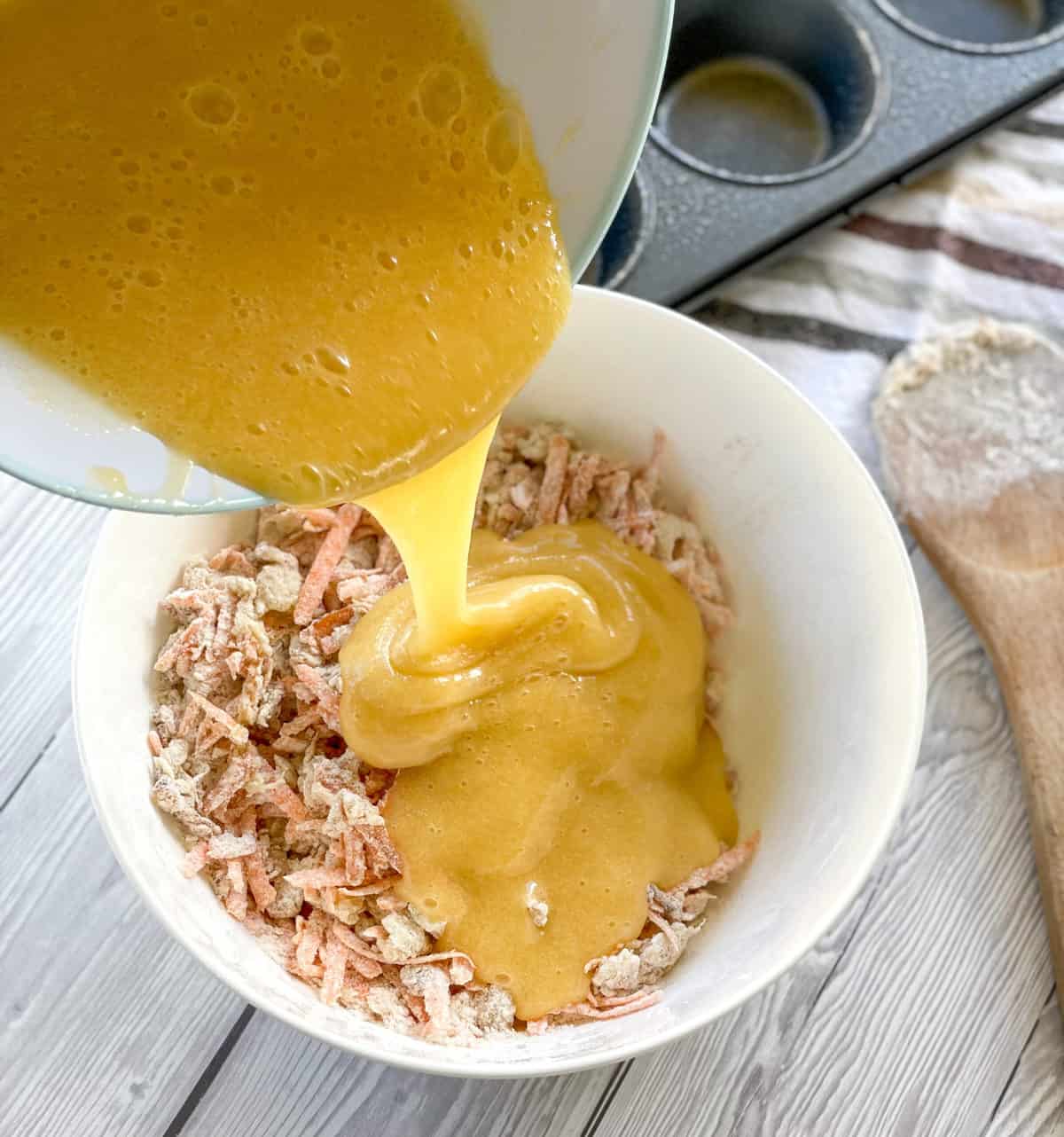 pouring the emulsion of eggs, oil and sugar into the dry ingredients for the carrot and pineapple muffins 