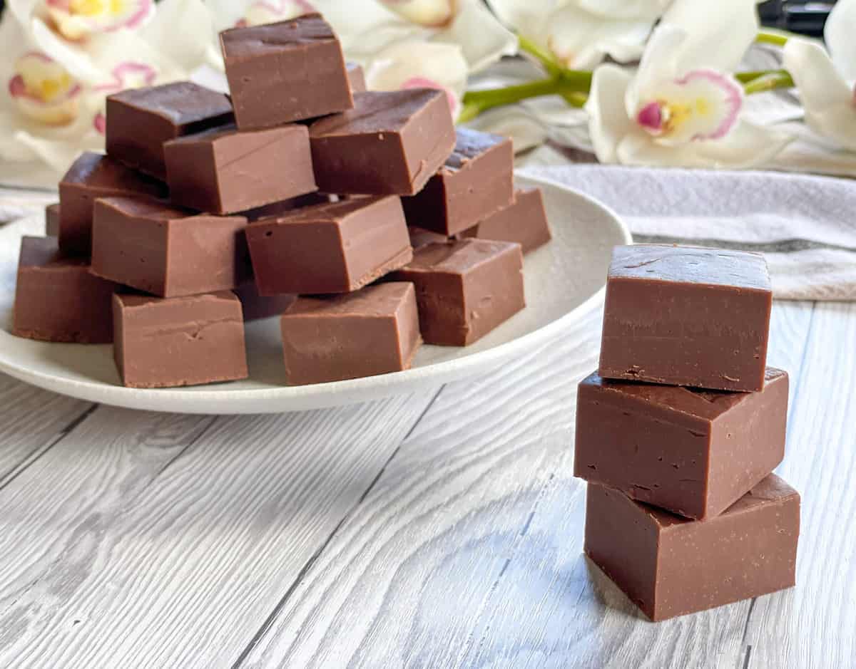 A white plate filled with white chocolate fudge and a stack of three pieces