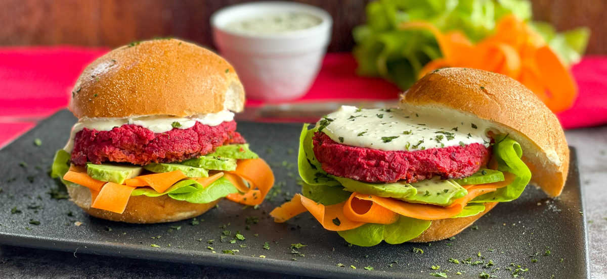 Fresh delicious burgers with beetroot patties, whipped feta and vegetables on a black plate 