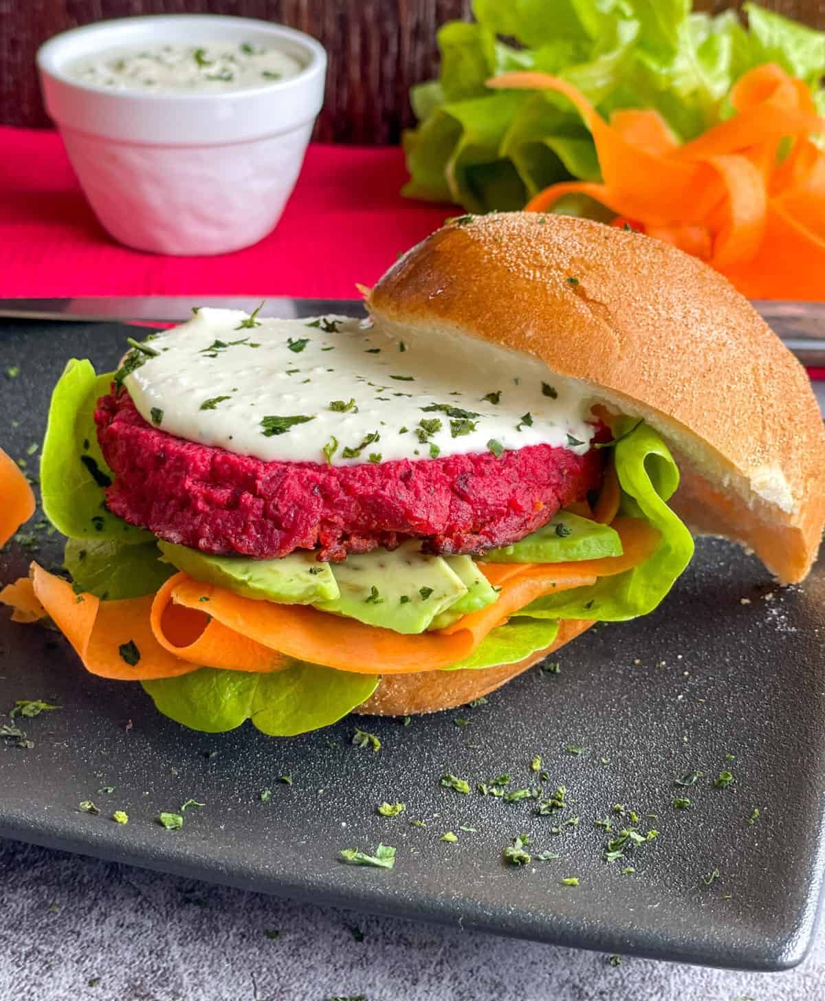 Beetroot Burger served on a toasted bun with whipped feta, avocado, lettuce and carrot 