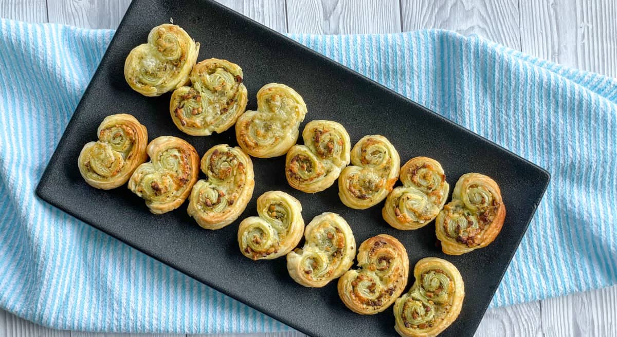 Golden brown savoury Palmier on a black plate. 