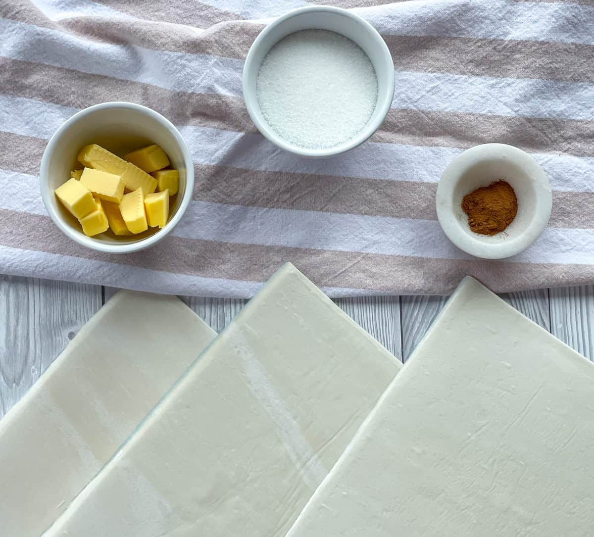 Ingredients needed for sweet palmiers, puff pastry sheets, butter, sugar and cinnamon