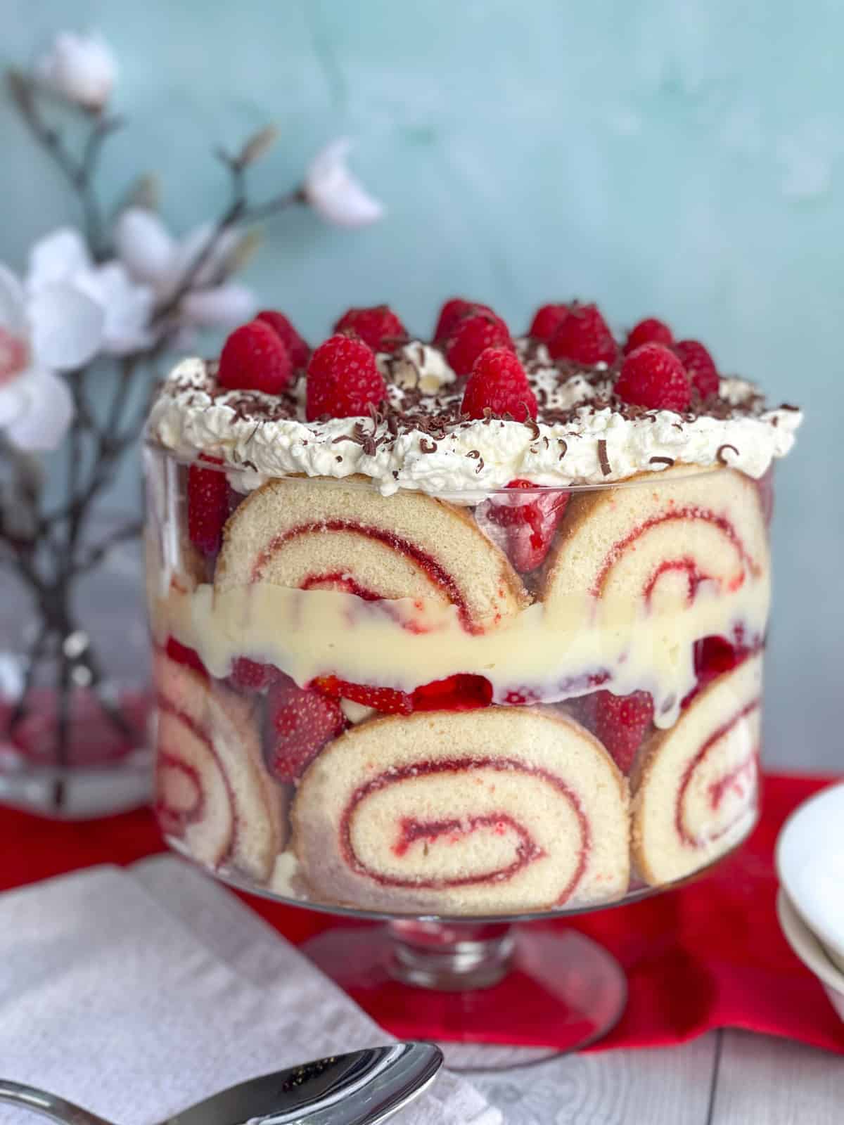 Large glass trifle bowl filled with traditonal classic trifle topped with whipped cream and berries 