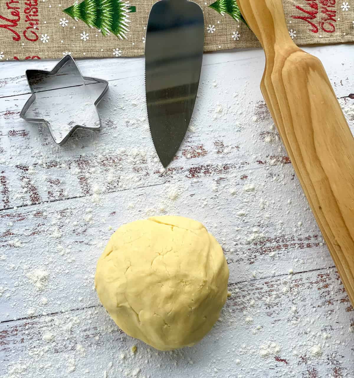 A ball of shortbread dough and rolling pin on a floured surface 