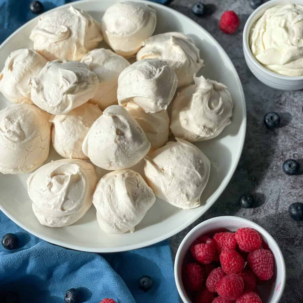 Bowl of crispy chewy meringues, cream and raspberries 