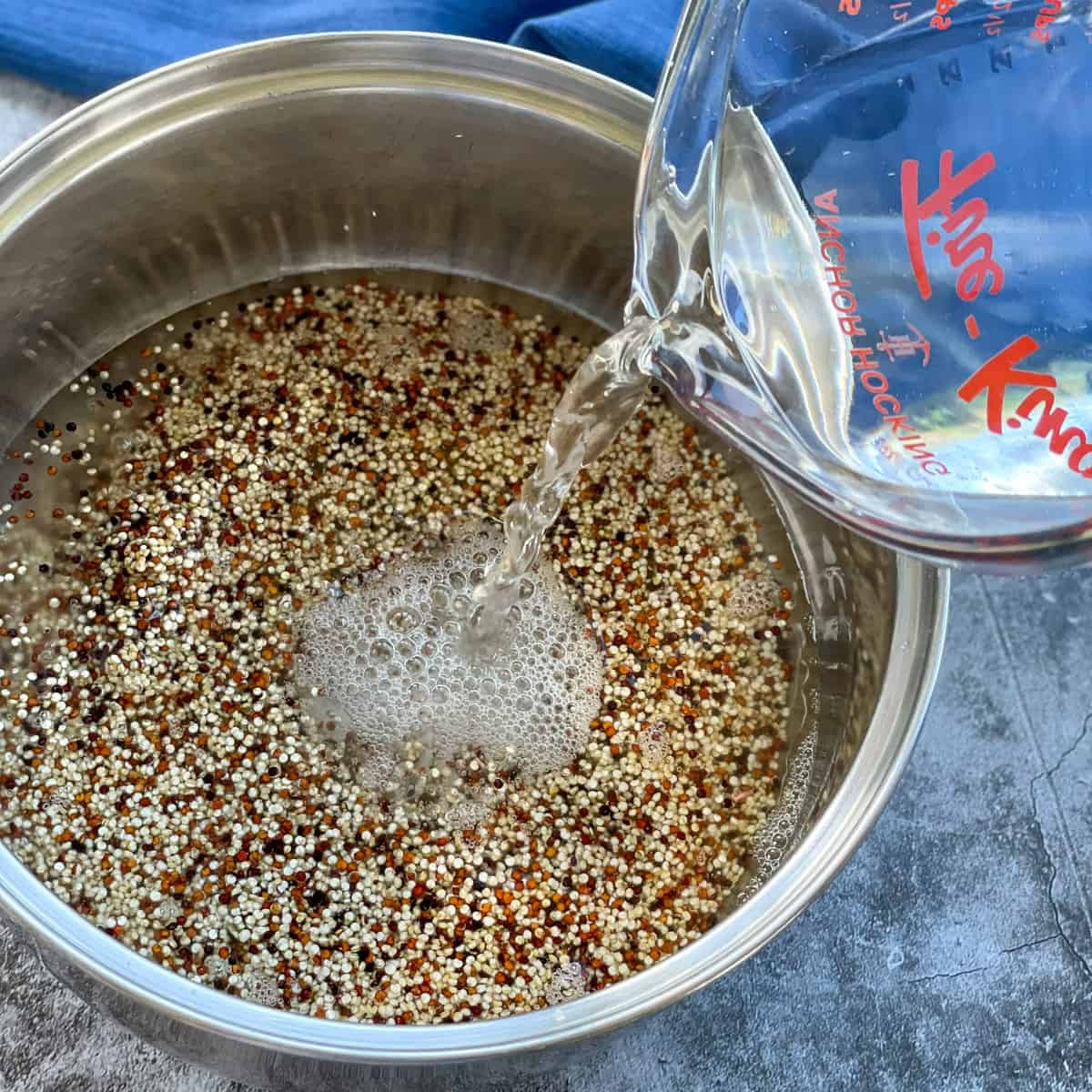 Pouring water over a saucepan with quinoa before cooking 