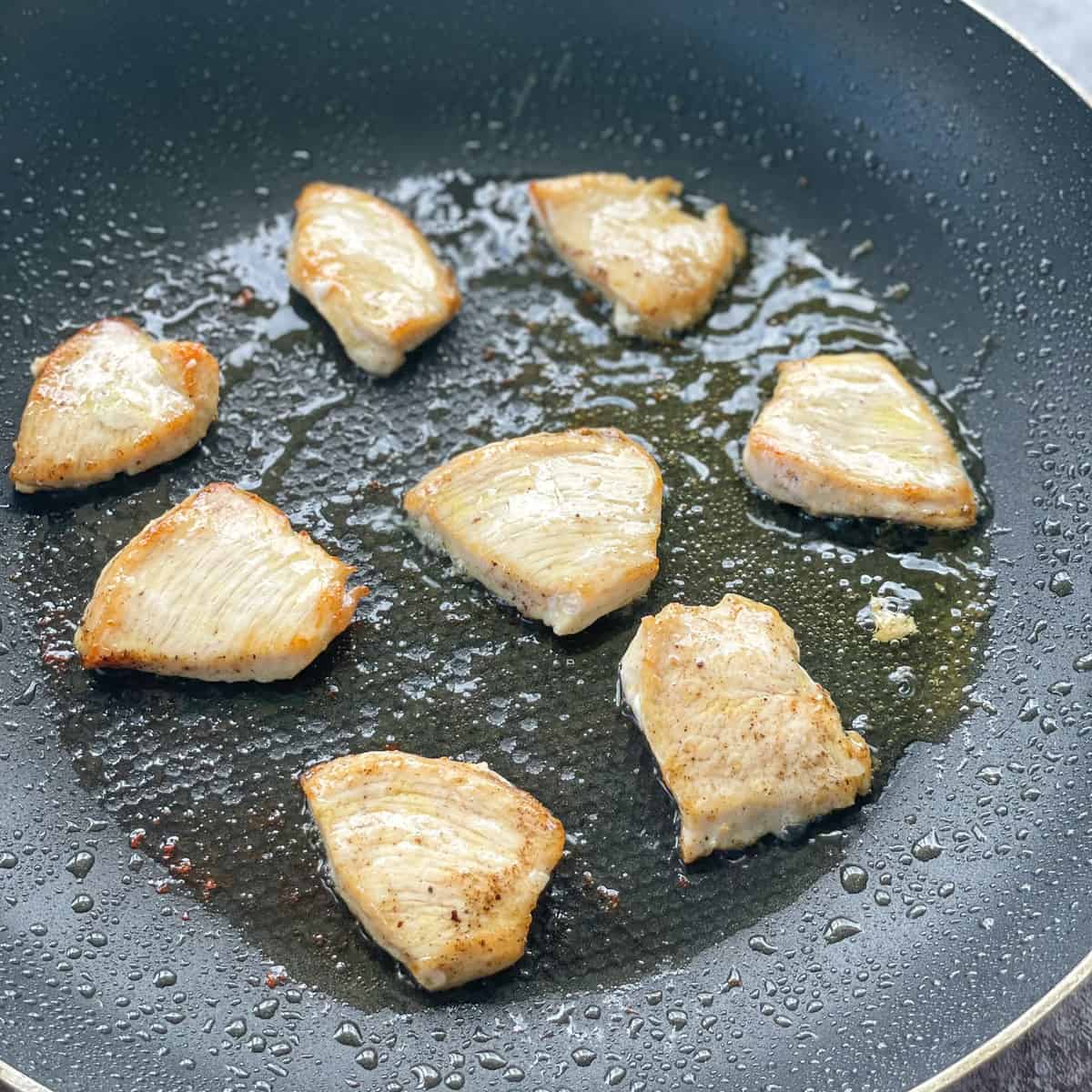 Panfrying slices of seasoned chicken breast