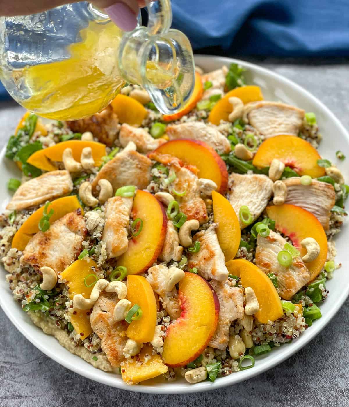 Pouring a lemon oil dressing over the quinoa salad 